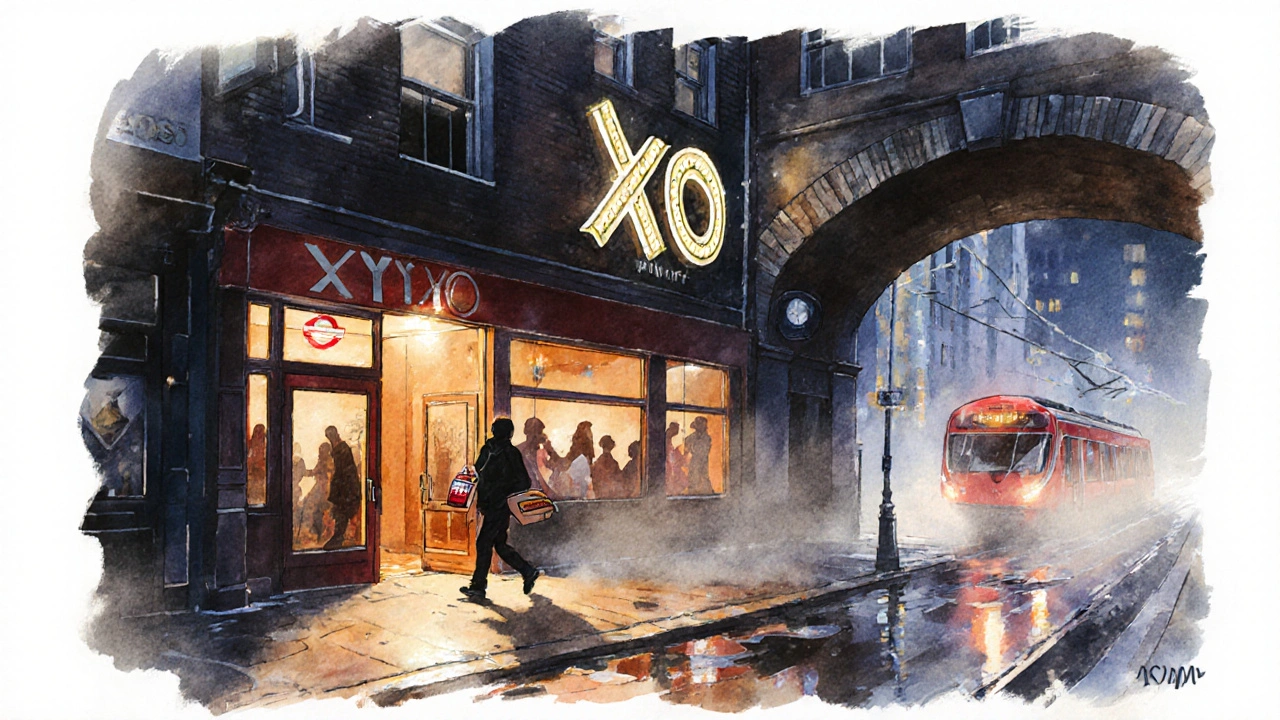 Nighttime exterior of XOYO under railway arches, person exiting with kebab, soft light glowing on wet pavement.