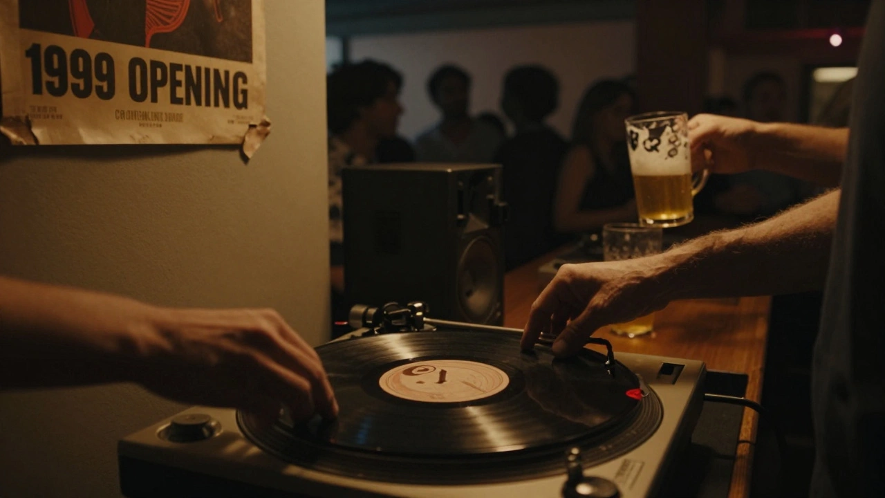 Close-up of hands placing a vinyl record on a turntable in a dimly lit club, with a blurred crowd swaying behind.